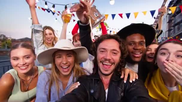 Joven hombre caucásico haciendo vídeo con sus amigos en una fiesta con el teléfono inteligente. Amigos de fiesta en la azotea divirtiéndose, cantando y bailando juntos. — Vídeo de stock