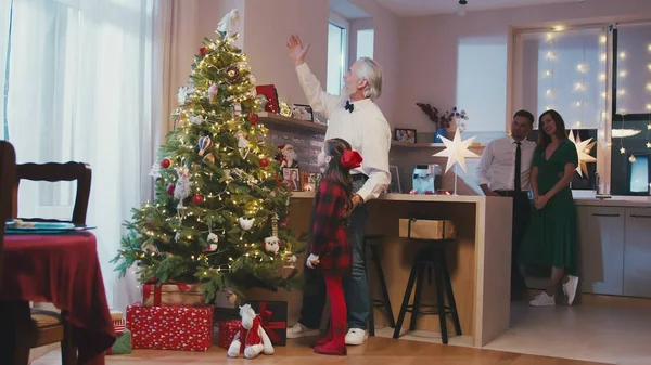 Heureux grand-père et petite-fille suspendus décorations à l'arbre de Noël à Noël ou Nouvel An fête à la maison. Préparation des fêtes de Noël ou vacances d'hiver. — Photo