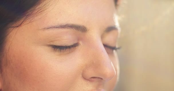 Primer plano de bonita cara femenina con ojos marrones oscuros que se abren al aire libre. Mujer adulta bañándose en rayos de sol, respirando con aire fresco en la calle. Libertad, estilo de vida, concepto de naturaleza. — Vídeo de stock