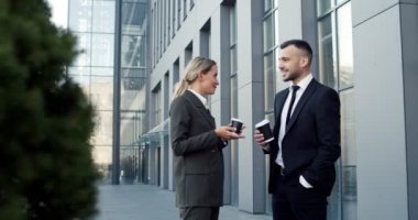 Beyaz, neşeli, genç bir çift iş ortağı şehrin sokaklarında yürüyor, konuşuyor ve gülümsüyor. İş arkadaşları sabah işe gidecekler.