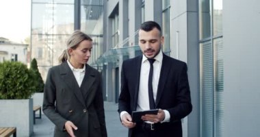 Kafkasyalı iş adamları sokakta birbirleriyle sohbet ediyorlarmış. Adam dışarıda asistanına tablet ekranda bir şey gösteriyor.