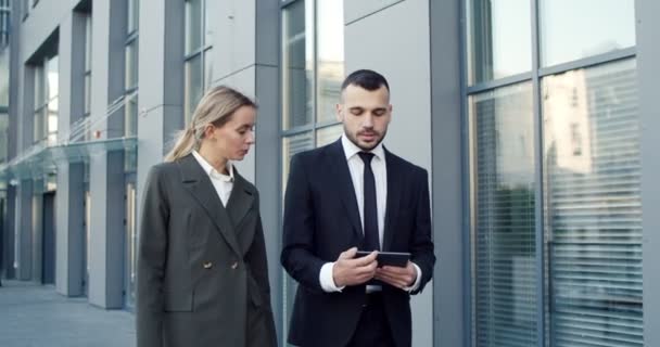 Hombre de negocios caucásico y mujer de negocios mirando la pantalla de la tableta mientras trabaja al aire libre la oficina en la ciudad — Vídeos de Stock