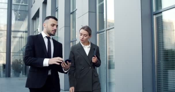 Homem de negócios caucasiano e mulher de negócios olhando para a tela do tablet enquanto trabalhava ao ar livre no escritório na cidade — Vídeo de Stock