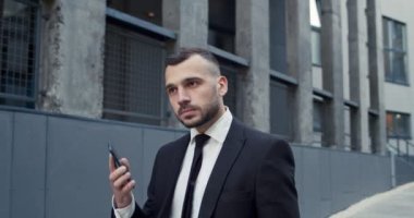 Şehirde yürüyen ve akıllı telefondan konuşan Kafkas asıllı ciddi bir erkeğin portresi. Sokakta cep telefonuyla konuşan yakışıklı bir menajer. İş adamı kavramı