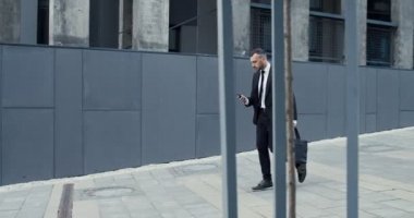 İş merkezinin yakınında açık havada koşarken elinde akıllı telefon tutan meşgul erkek yöneticinin tam boy görüntüsü. Kafkasyalı işadamı acele et.
