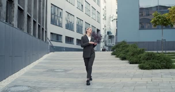 Joyeux jeune femme d'affaires caucasienne marchant en ville à l'extérieur tout en dansant et en ayant une bonne humeur. Travailleuse s'amusant terminé journée de travail — Video