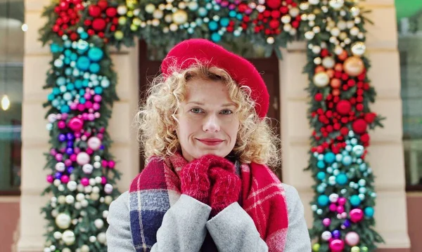 Belle femme debout sur la rue décorée, regardant et souriant à la caméra. Concept humeur de Noël. — Photo