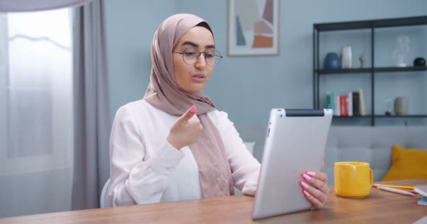 Mellanplan för unga muslimska kvinnor som sitter och tittar på kameran på en mobil pekplatta som kommunicerar med vänner via internet och ringer videosamtal. Livsstil, modern islam koncept. — Stockvideo