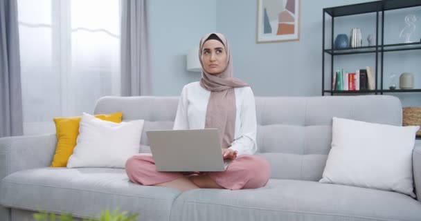 Mellanplan för smart ung muslim student i hijab arbetar med dator, söka på Internet, surfa, ser eftertänksamt. Arabiska kvinna tänker, drömmer, mediterar, vilse i tanken. — Stockvideo