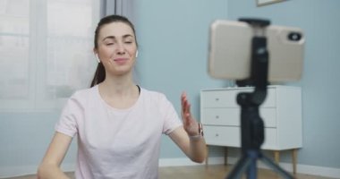 Genç kadın fitness eğitmeninin spor giyim programının orta planı evde çalışmak için kamera eğitimine kaydedildi. Bloger akışı işe yarıyor. Kadın evde antrenman yapıyor. İnsanlar ve aktif yaşam tarzı kavramı.