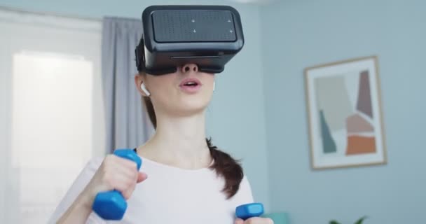 Close up portrait of athletic female doing exercises with VR glasses at home. Woman wearing VR glasses connected to virtual reality personal trainer. Sport and fitness. Training, workout and wellness. — Vídeo de Stock