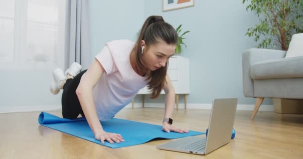 Formda bir kadının spor yapması ve sağlıklı bir yaşam tarzı için egzersiz yapması ve güçlü ellerin bilgisayarında online eğitim izlemesi ve kulaklık kullanması. Sağlıklı ve spor yaşam tarzı. — Stok video