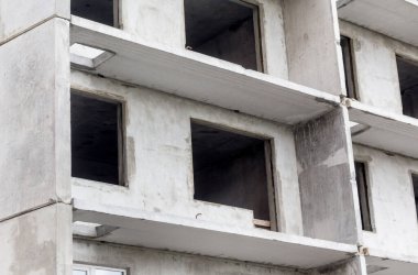 Modern bir binanın ön cephesi yapım aşamasında. Çok katlı bir bina yapım aşamasında. İnşaat konsepti. Yakın görünüm.