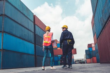 Endüstriyel işçiler, deniz aşırı nakliye konteynır sahasında iş arkadaşlarıyla çalışıyor.