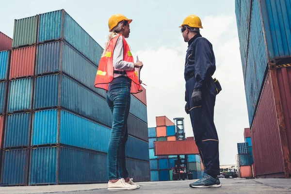 Endüstriyel işçiler, deniz aşırı nakliye konteynır sahasında iş arkadaşlarıyla çalışıyor.