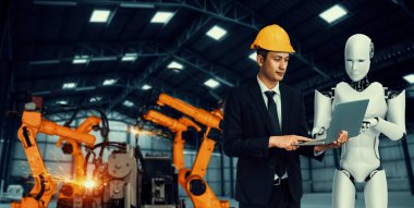 Mekanize endüstri robotu ve insan işçileri gelecekteki fabrikada birlikte çalışıyorlar.