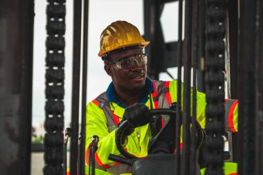 Tersanede forklift kullanan Afrikalı Amerikalı bir adam.