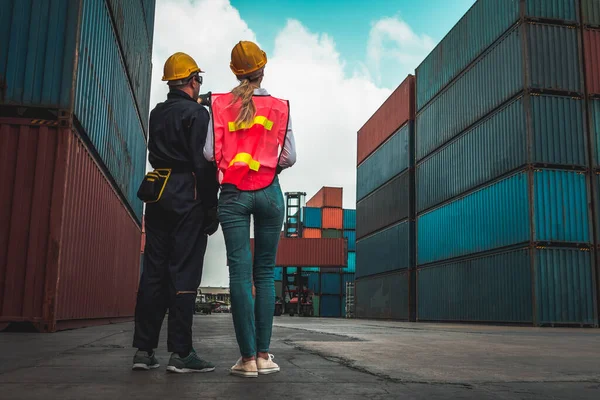 Industrial worker works with co-worker at overseas shipping container yard