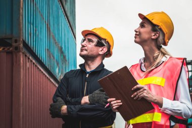 Endüstriyel işçiler, deniz aşırı nakliye konteynır sahasında iş arkadaşlarıyla çalışıyor.