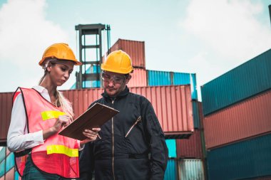 Endüstriyel işçiler, deniz aşırı nakliye konteynır sahasında iş arkadaşlarıyla çalışıyor.