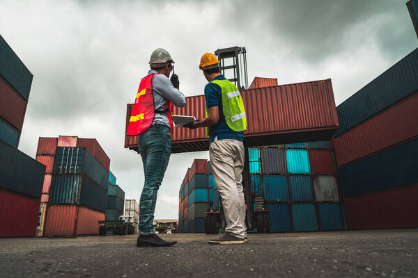 Industrial worker works with co-worker at overseas shipping container yard