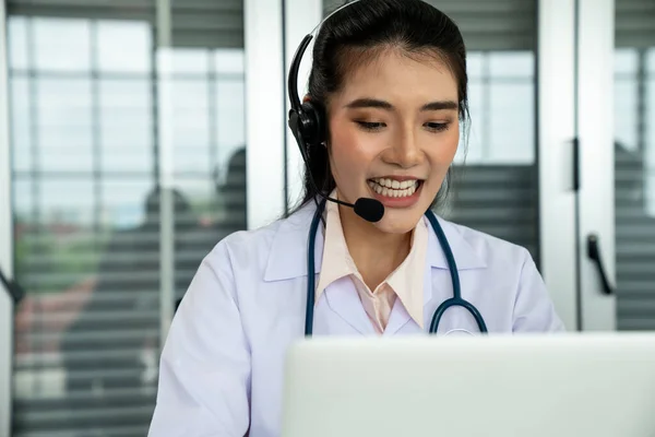 Medico indossando auricolare parlando attivamente in videochiamata in ospedale o in clinica — Foto Stock