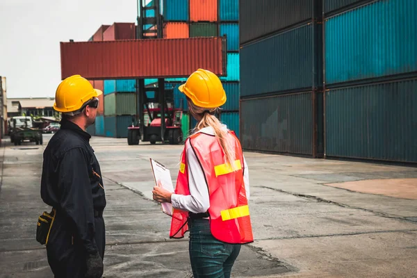 Trabajador industrial trabaja con su compañero de trabajo en el patio de contenedores de envío en el extranjero — Foto de Stock