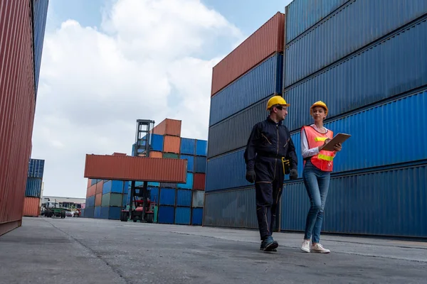 Industrial worker works with co-worker at overseas shipping container yard