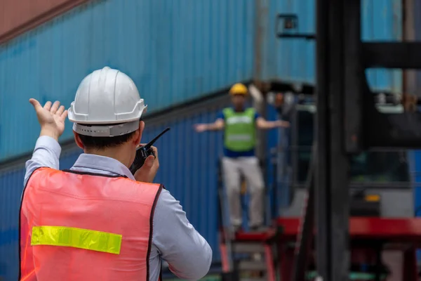 Trabajador industrial trabaja con su compañero de trabajo en el patio de contenedores de envío en el extranjero — Foto de Stock