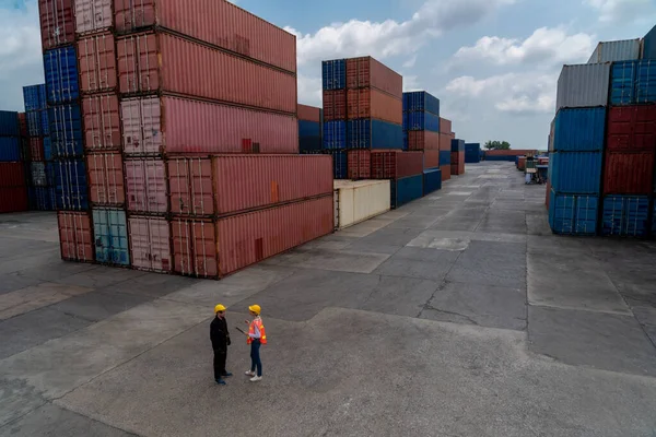 Industrial worker works with co-worker at overseas shipping container yard