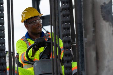 Tersanede forklift kullanan Afrikalı Amerikalı bir adam.