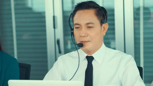 Homem de negócios usando fone de ouvido trabalhando ativamente no escritório — Fotografia de Stock