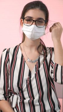 Genç bir kadın yüzünden maskesini çıkarıyor.