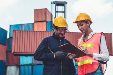 Endüstriyel işçiler, deniz aşırı nakliye konteynır sahasında iş arkadaşlarıyla çalışıyor.