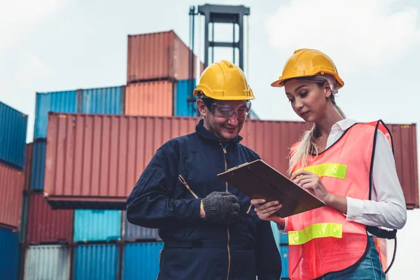 Endüstriyel işçiler, deniz aşırı nakliye konteynır sahasında iş arkadaşlarıyla çalışıyor.