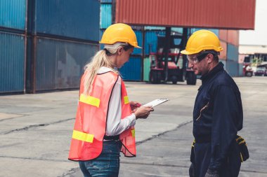 Endüstriyel işçiler, deniz aşırı nakliye konteynır sahasında iş arkadaşlarıyla çalışıyor.