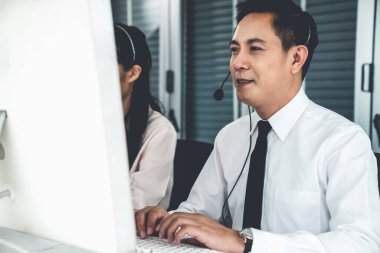 Kulaklık takan bir işadamı aktif olarak ofiste çalışıyor.