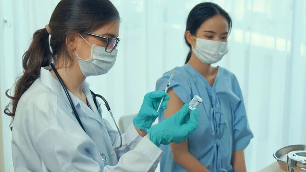 Young woman visits skillful doctor at hospital for vaccination