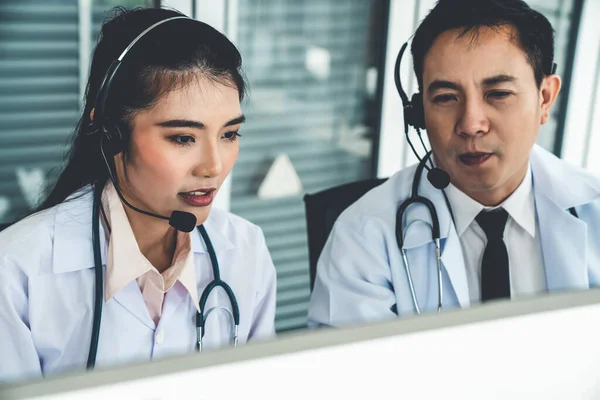 Equipe médica usando fone de ouvido conversando ativamente em videochamada na clínica do hospital — Fotografia de Stock
