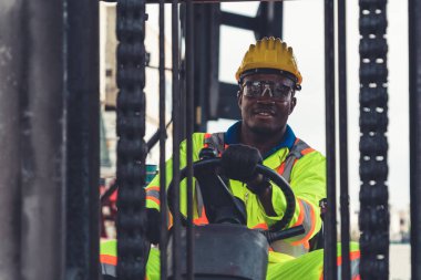 Tersanede forklift kullanan Afrikalı Amerikalı bir adam.