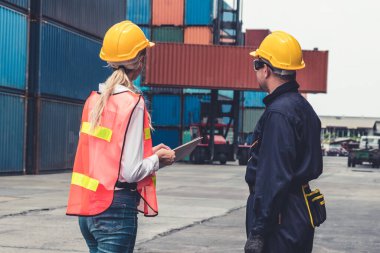 Endüstriyel işçiler, deniz aşırı nakliye konteynır sahasında iş arkadaşlarıyla çalışıyor.