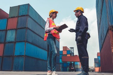 Endüstriyel işçiler, deniz aşırı nakliye konteynır sahasında iş arkadaşlarıyla çalışıyor.