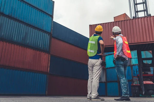 Trabajador industrial trabaja con su compañero de trabajo en el patio de contenedores de envío en el extranjero — Foto de Stock