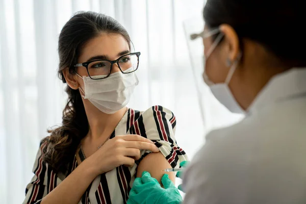 Young woman visits skillful doctor at hospital for vaccination