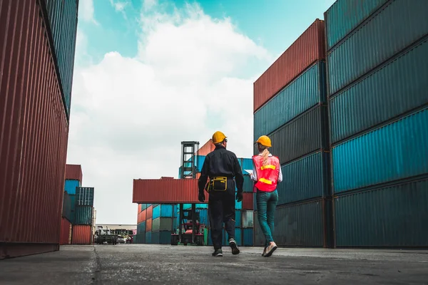 Trabajador industrial trabaja con su compañero de trabajo en el patio de contenedores de envío en el extranjero — Foto de Stock