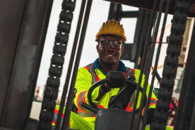 Tersanede forklift kullanan Afrikalı Amerikalı bir adam.