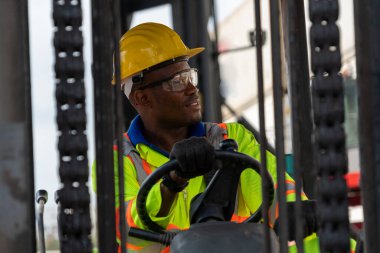 Tersanede forklift kullanan Afrikalı Amerikalı bir adam.
