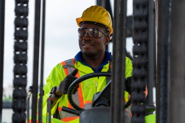 Tersanede forklift kullanan Afrikalı Amerikalı bir adam.