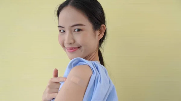 Молодая азиатка весело показывает повязку на вакцине COVID-19 — стоковое фото