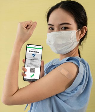Genç Asyalı kadın cep telefonunda aşı pasaportu gösteriyor.